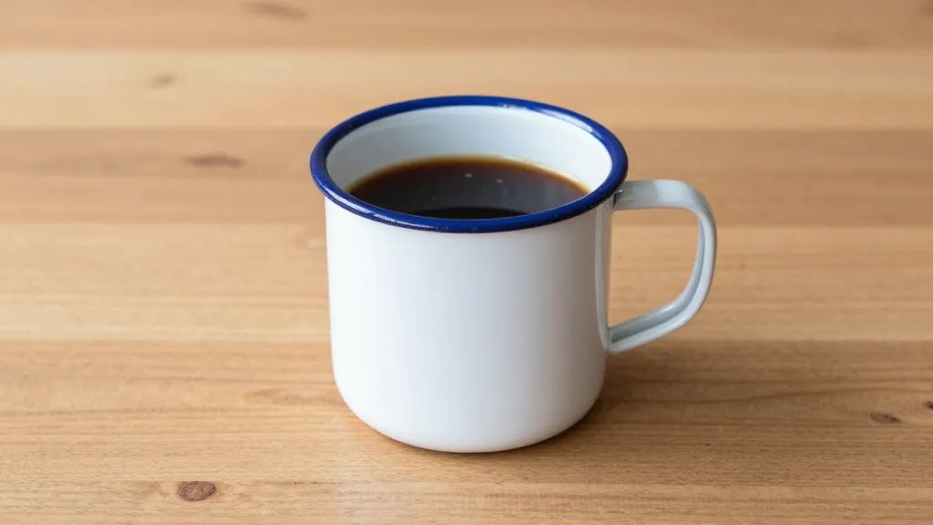 Single enamel camping mug with coffee on wooden table